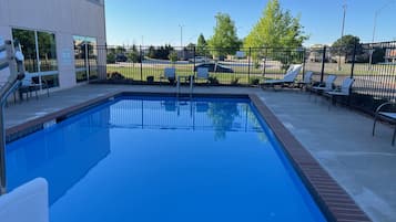Relax by the rectangular pool surrounded by lounge chairs and a deck area.
