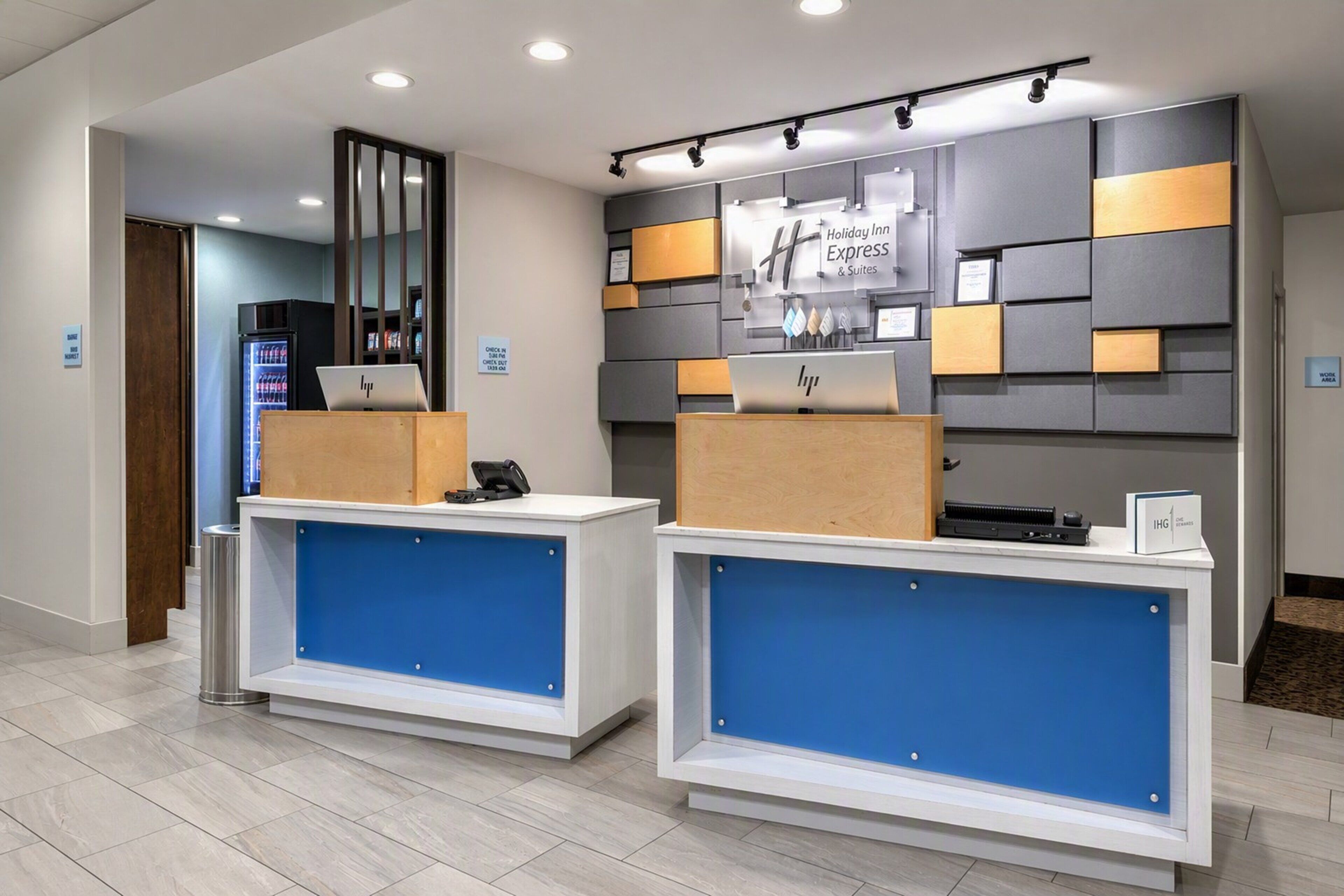 A reception area with two desks, a refrigerator, and a wall-mounted sign.