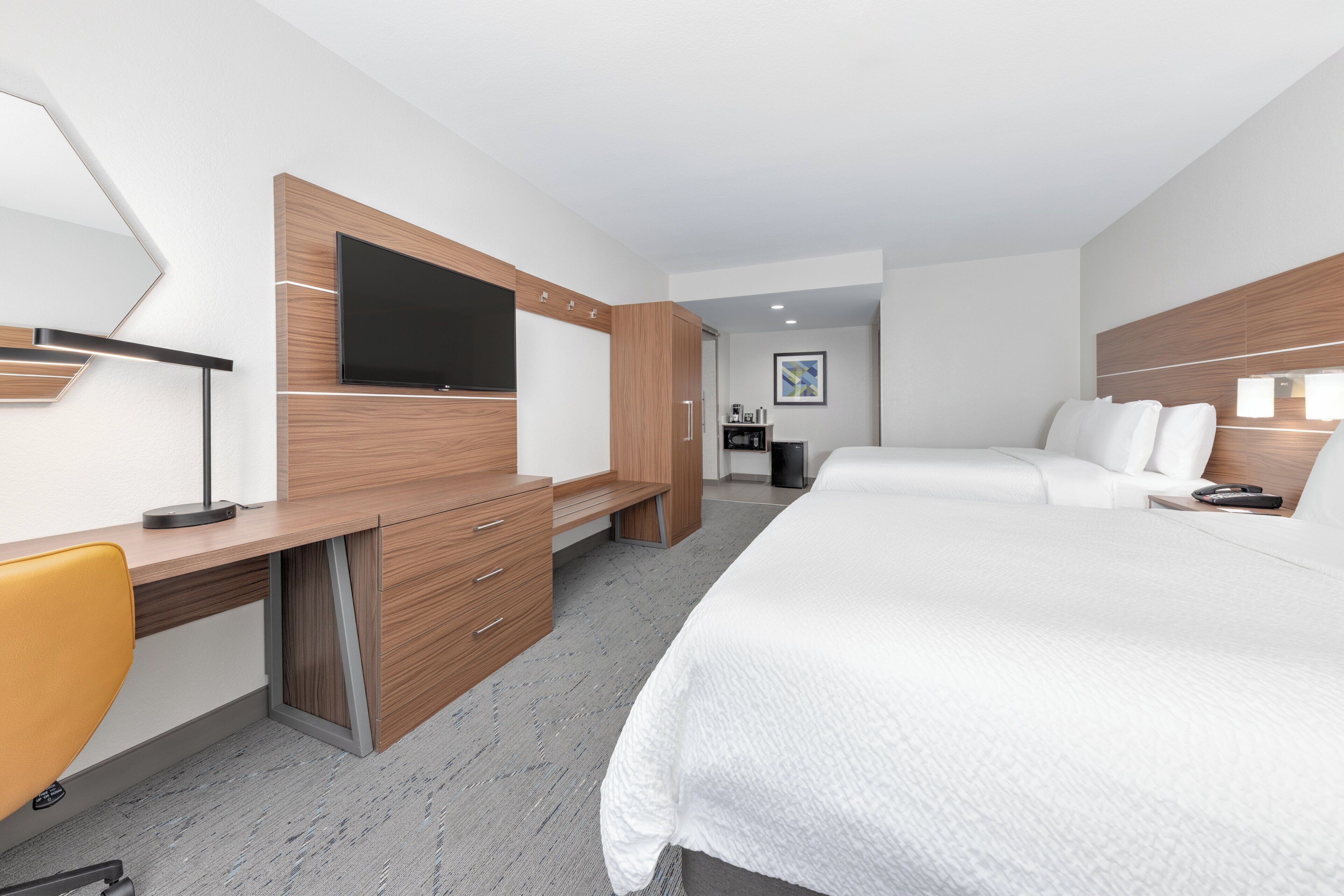 Habitació d'hotel moderna amb un llit gran, escriptori amb cadira, televisió i una petita zona d'esbarjo.