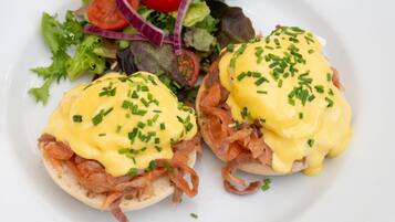 Un plato con huevos benedictinos y una ensalada acompañante.