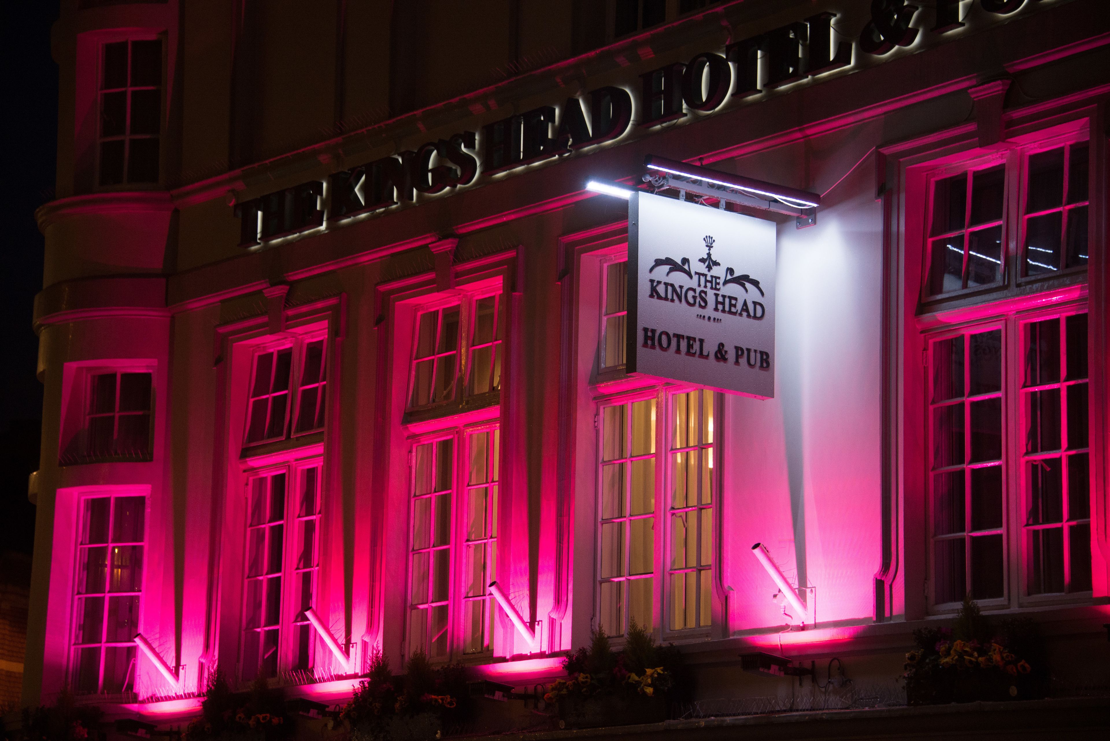 Hotel y pub The Kings Head con señalización iluminada e iluminación rosa.