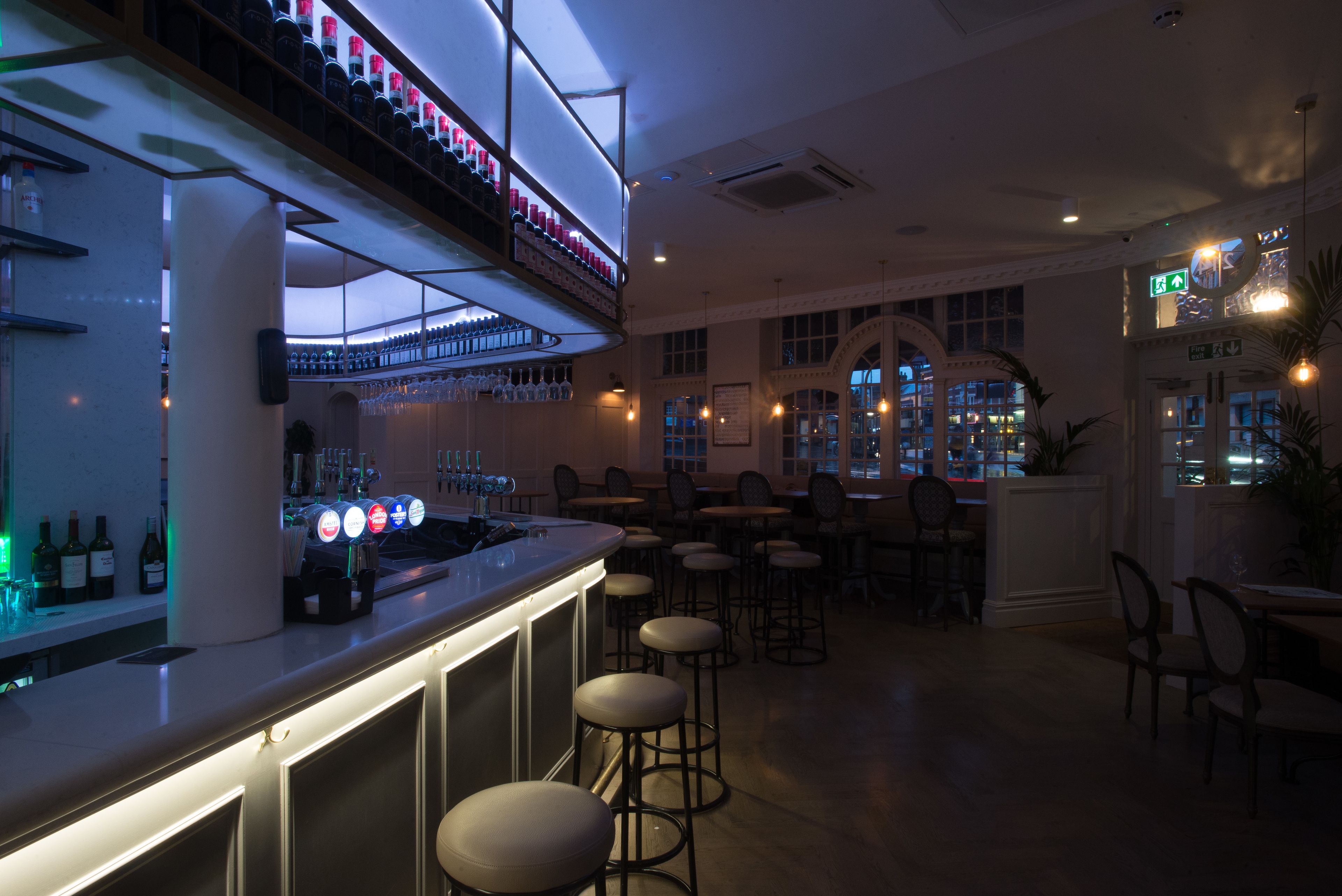 A bar area with a counter, stools, and shelves of bottles.