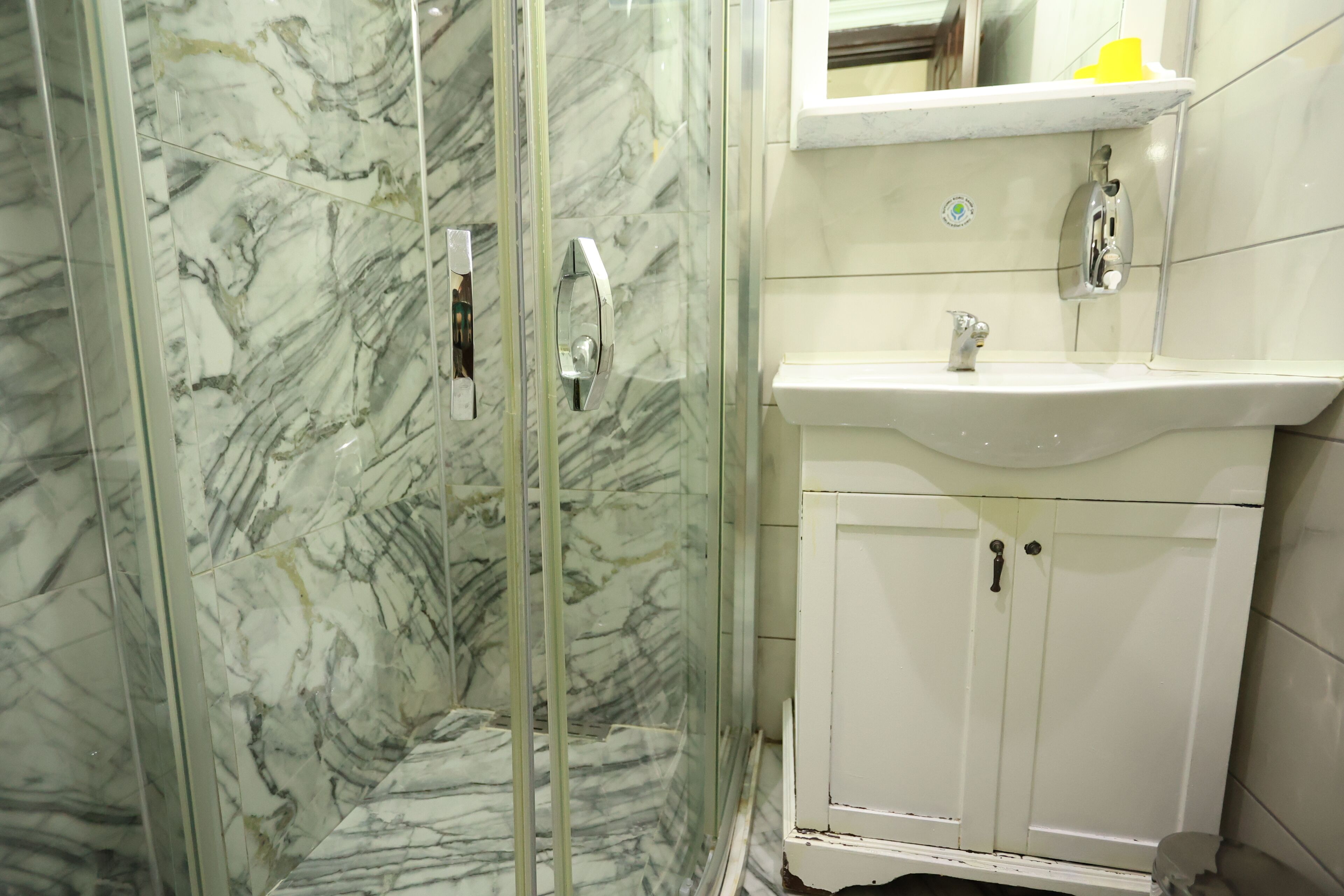 A bathroom with a glass-enclosed shower, a white sink, and a cabinet.