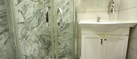 A bathroom with a glass-enclosed shower, a white sink, and a cabinet.