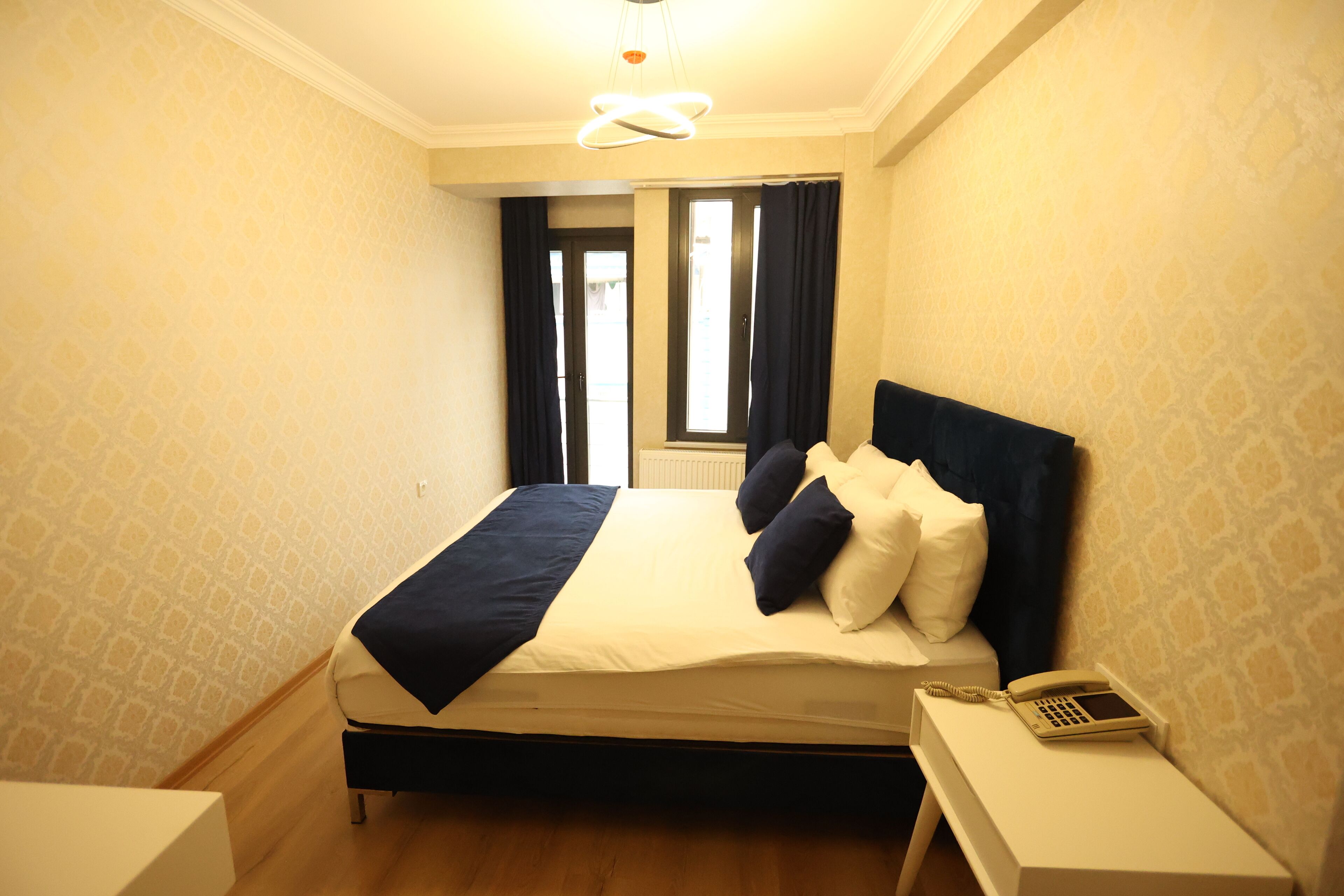 Ein Hotelzimmer mit einem Bett, einem Nachttischtelefon und Blick ins Freie durch ein Fenster.