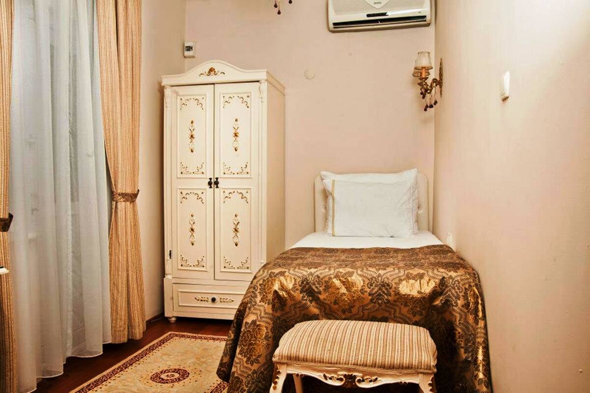 A bedroom with a bed, a white wardrobe, and a bench.