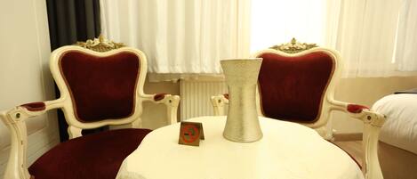 A room with two ornate chairs, a small table with a vase, and a sign indicating no smoking.
