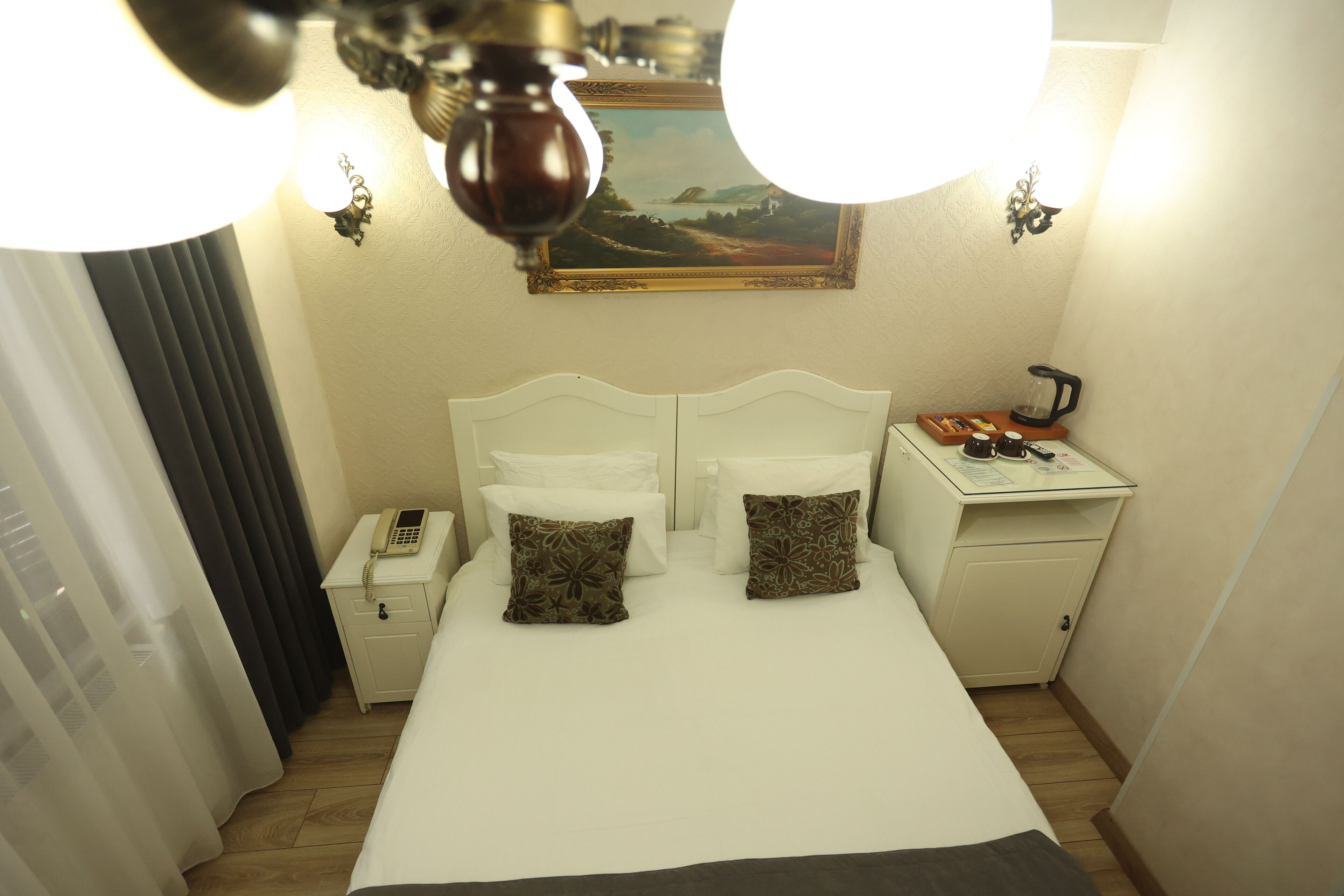Ein Hotelzimmer mit Bett, Nachttisch, Lampe und einem Bild an der Wand.