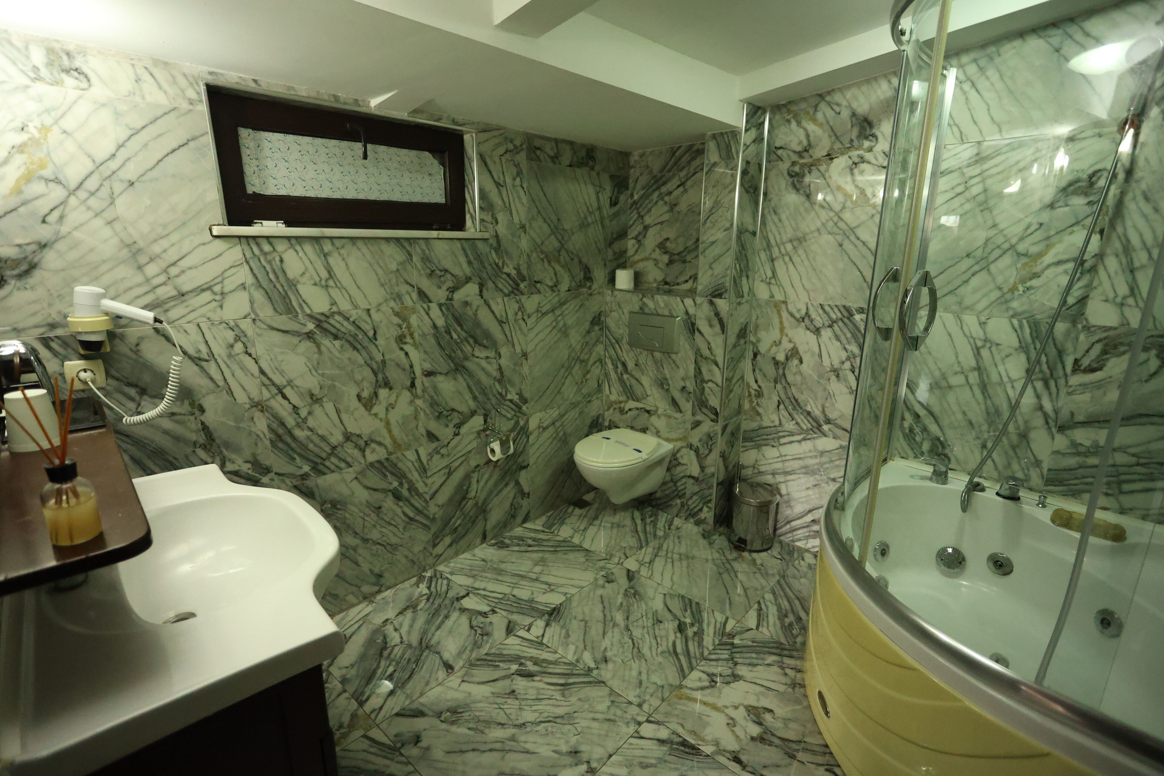A bathroom with a marble floor, a bathtub, a toilet, and a sink.