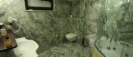 A bathroom with a marble floor, a bathtub, a toilet, and a sink.