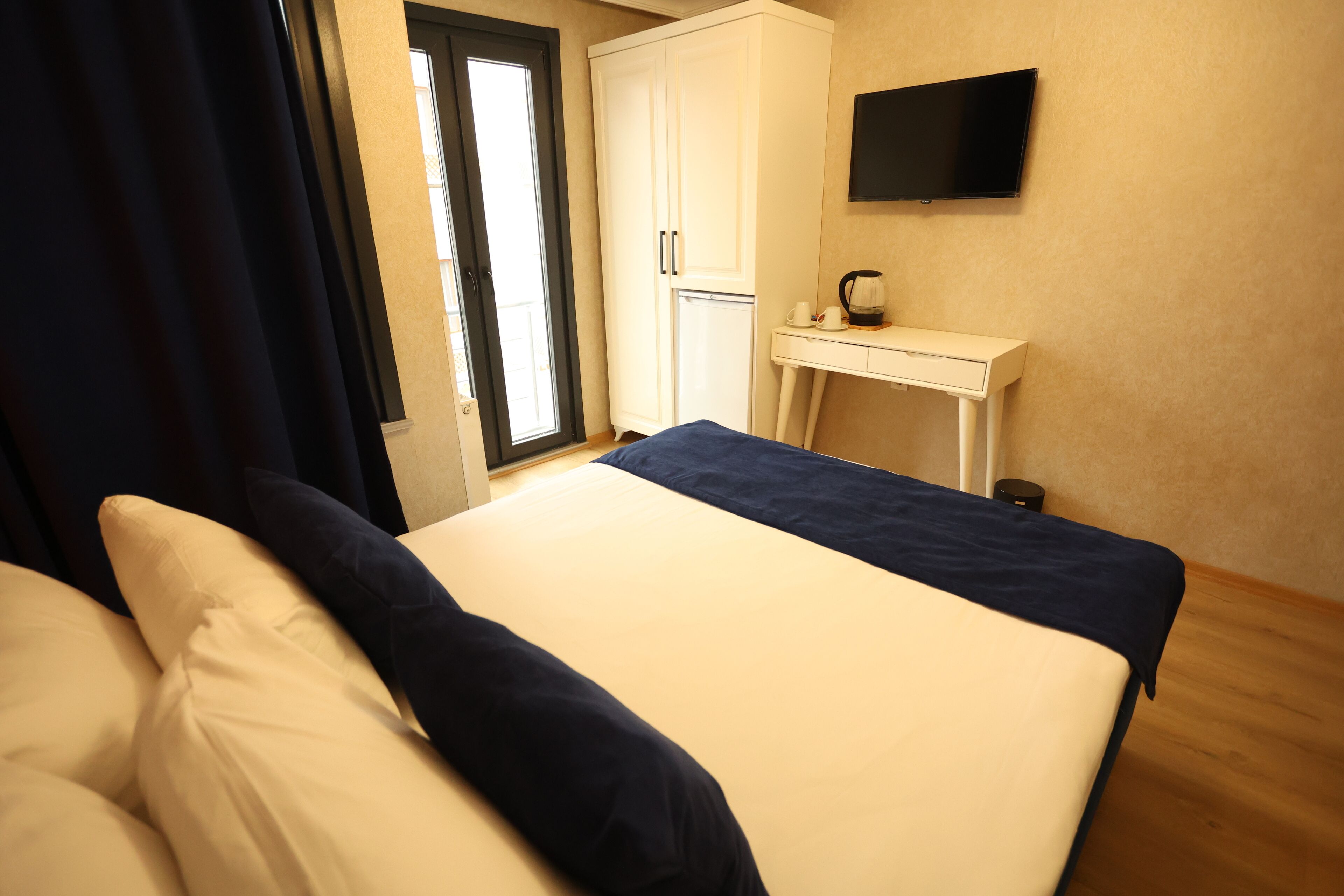 A bedroom with a bed, a desk, a television, and a wardrobe.
