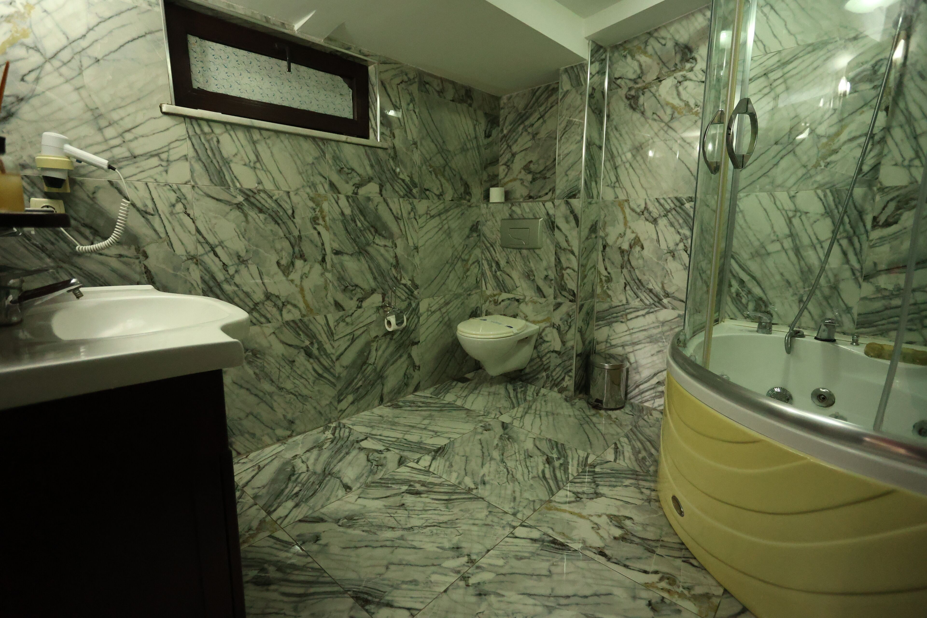 A bathroom with a marble floor, a bathtub, a toilet, and a sink.