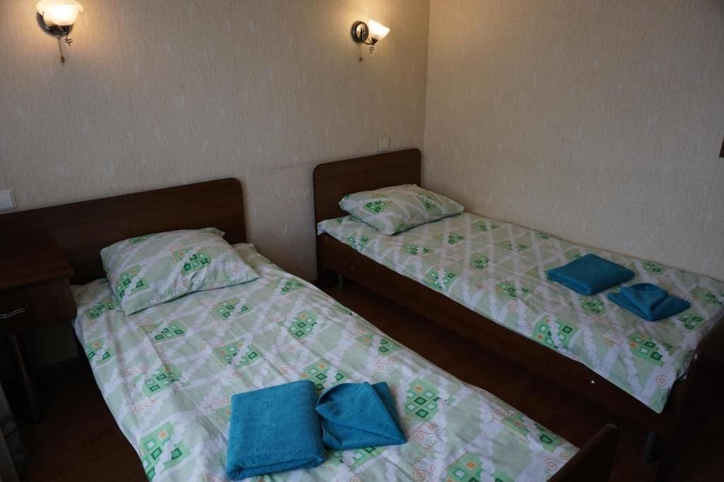 Two single beds with matching headboards and footboards, each with a pillow and a folded towel.