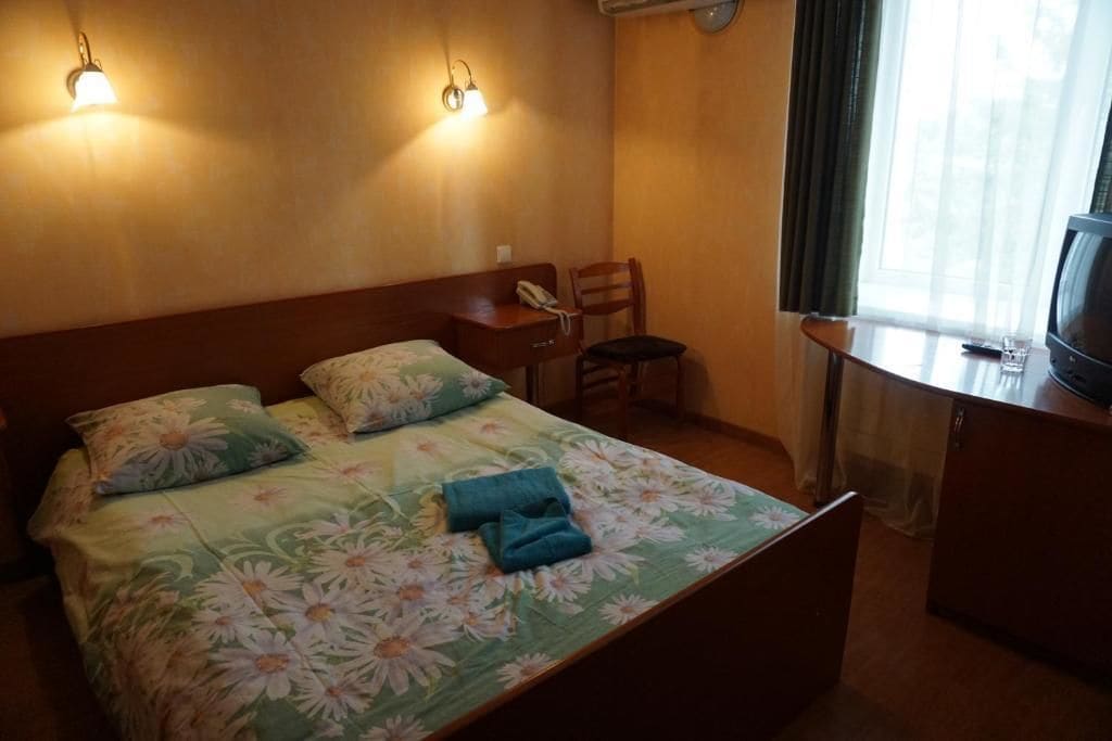 Een hotelkamer met een bed, een stoel, een bureau met telefoon en een televisie.