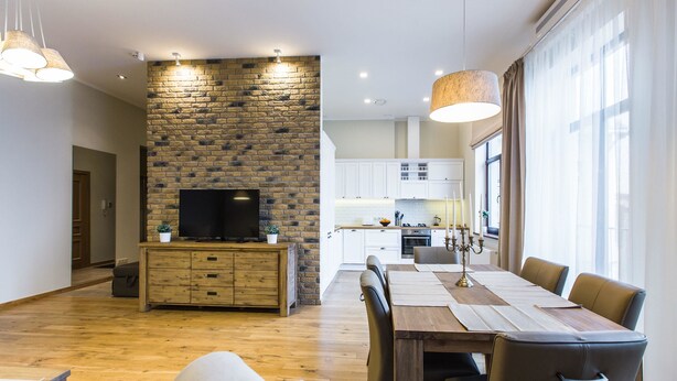 A modern living room with a stone wall, wooden furniture, and a TV. - Riga Lux Apartments - Ernesta (Riga)