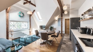 A modern kitchen with a large island, a dining area with a round table and chairs, and a view of the outdoors through a skylight.