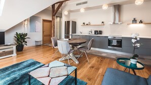 A modern kitchen with a dining area, wooden flooring, and a lofted living space.