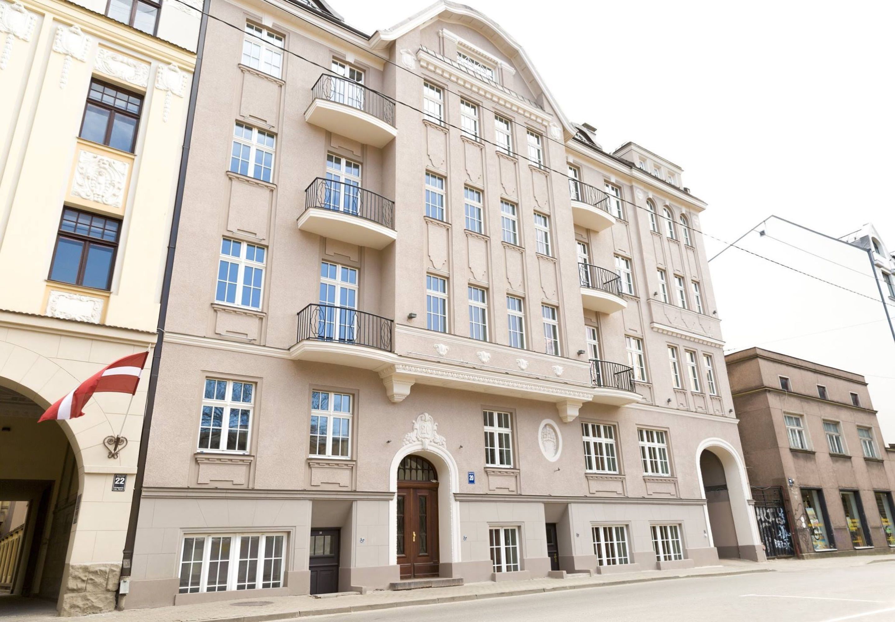 Un edificio de varios pisos con un estilo arquitectónico clásico, que cuenta con balcones, ventanas grandes y una entrada destacada con un arco.
