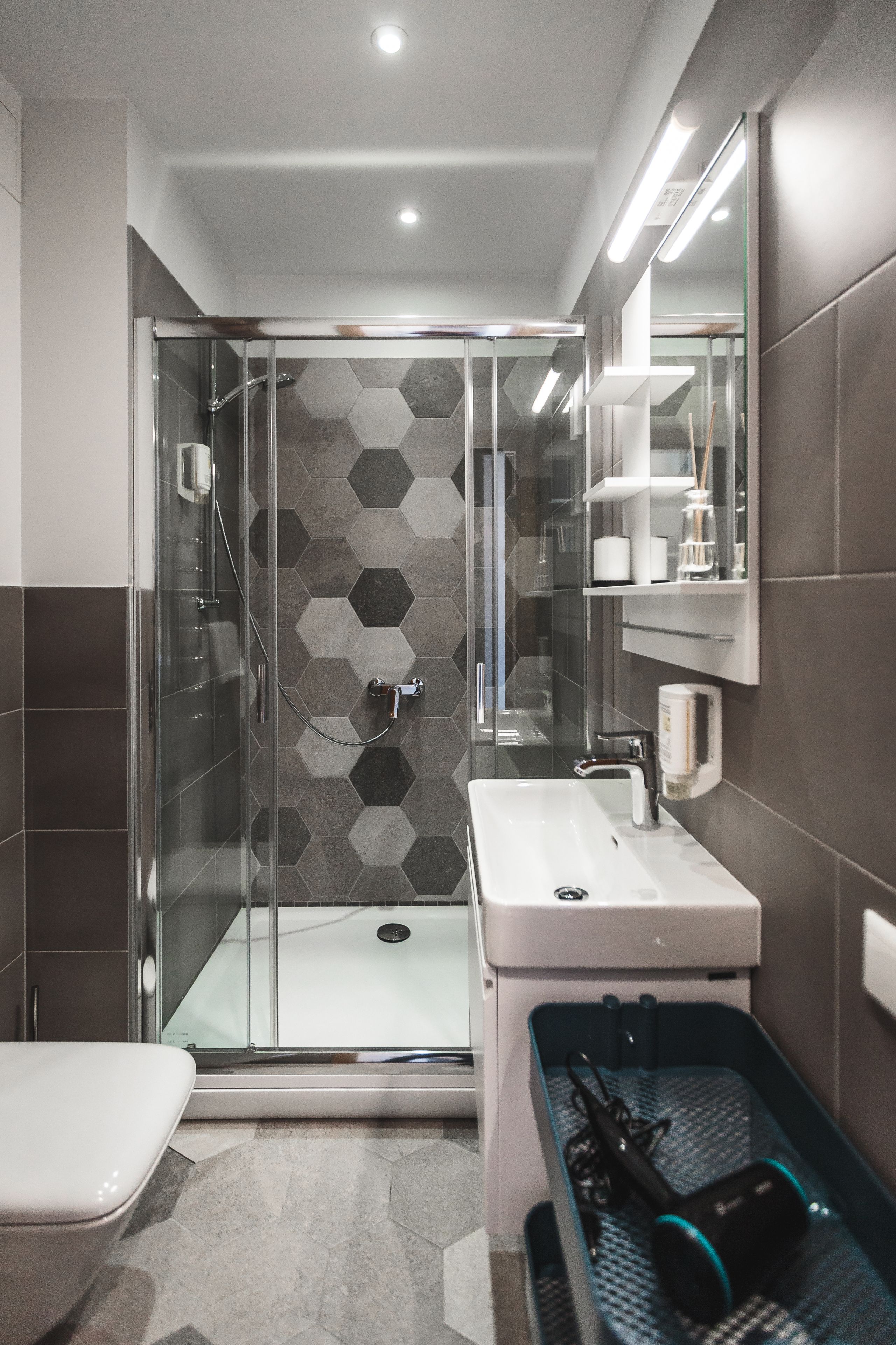 Een moderne badkamer met een douche met glazen wand, een wit wastafelmeubel en een spiegel erboven.