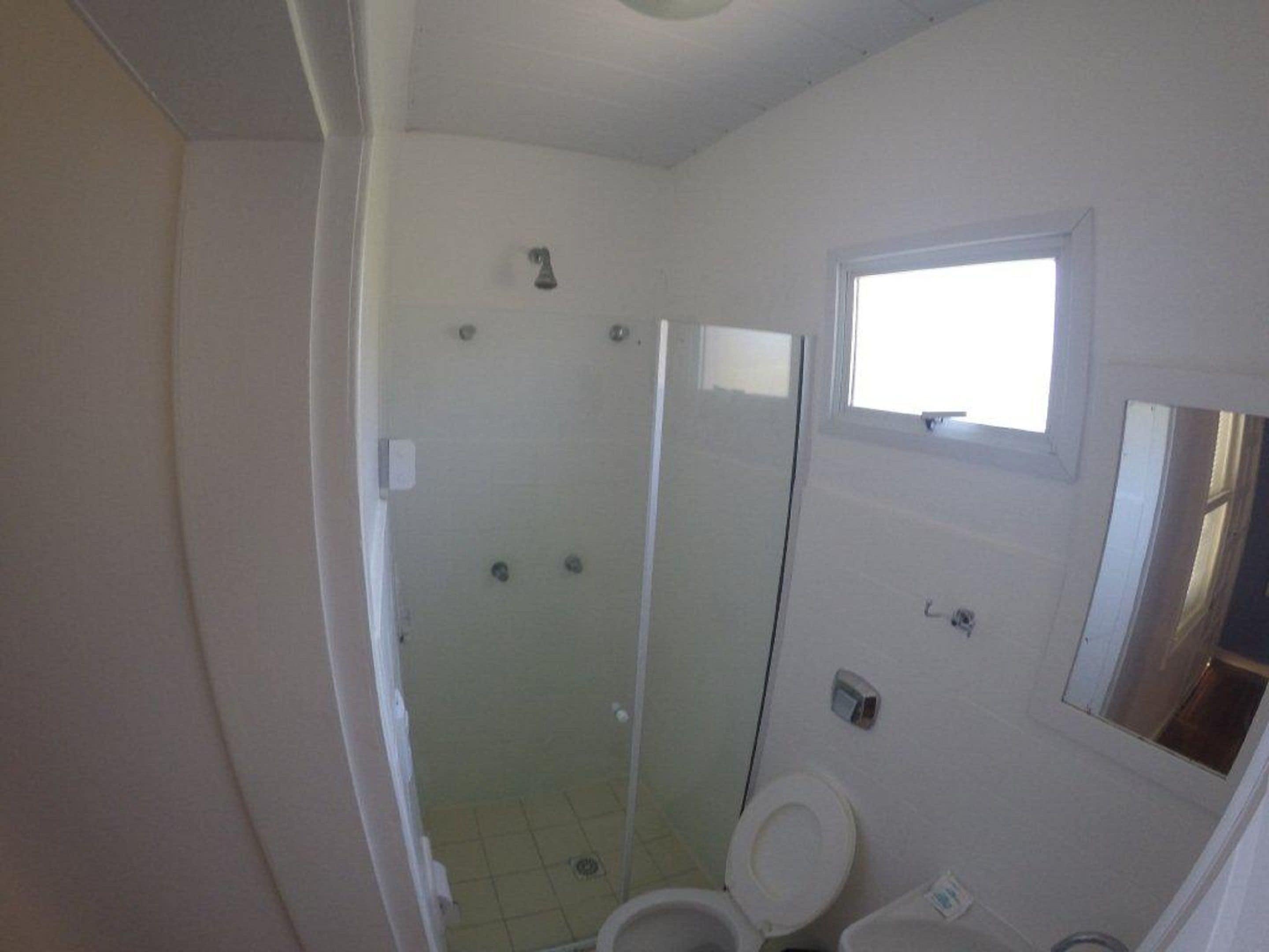 Kylpyhuone, jossa on suihku, wc ja pieni ikkuna.