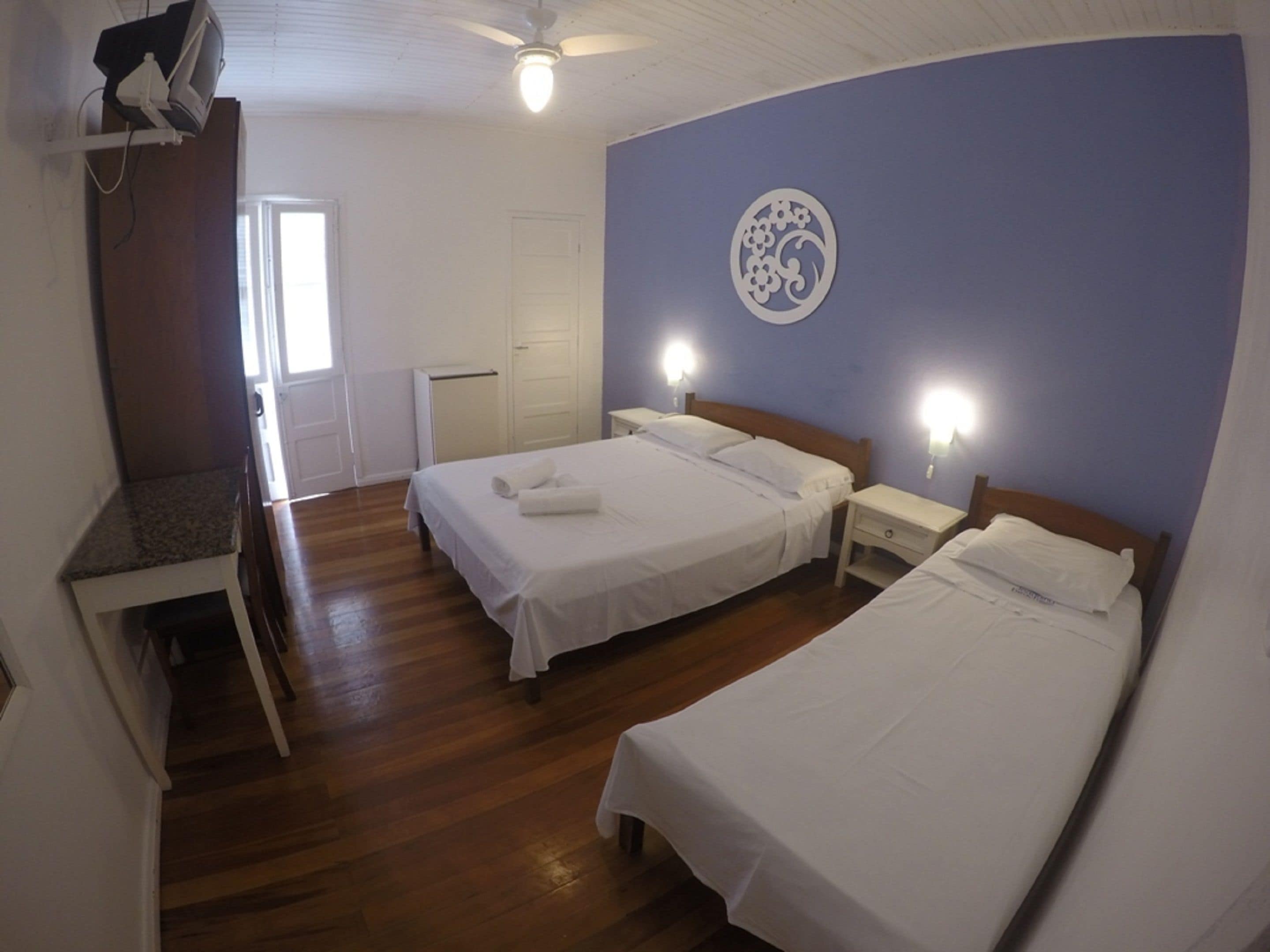 Un dormitorio con dos camas, un escritorio y un ventilador de techo.