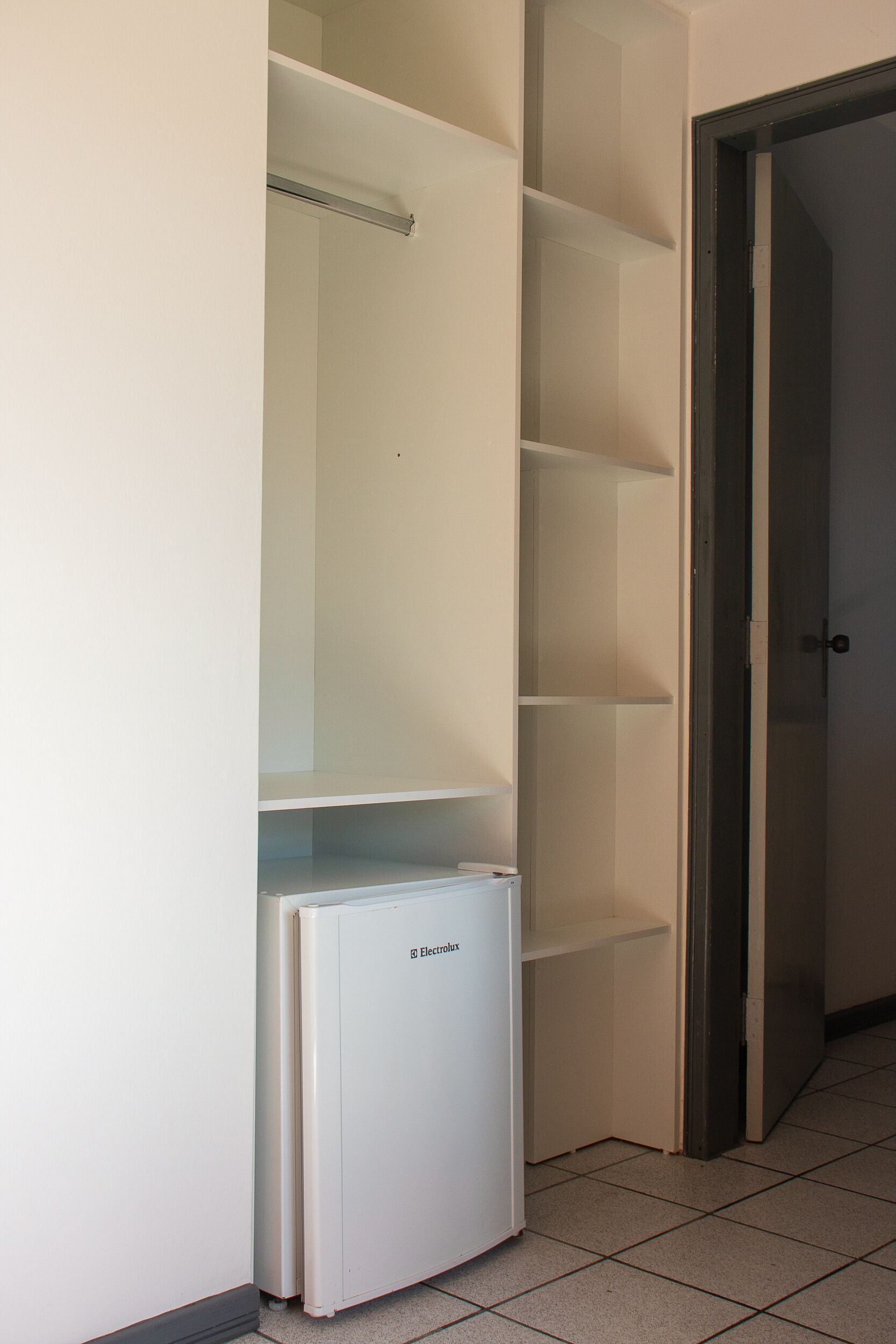 Una cocina compacta con un refrigerador blanco, horno empotrado y microondas.
