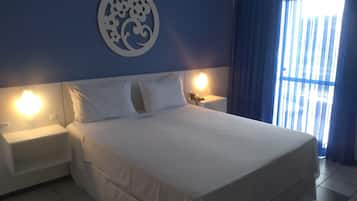 Ett hotellrum med en stor säng, två sängbord med lampor, en väggdekoration och ett fönster med gardiner.