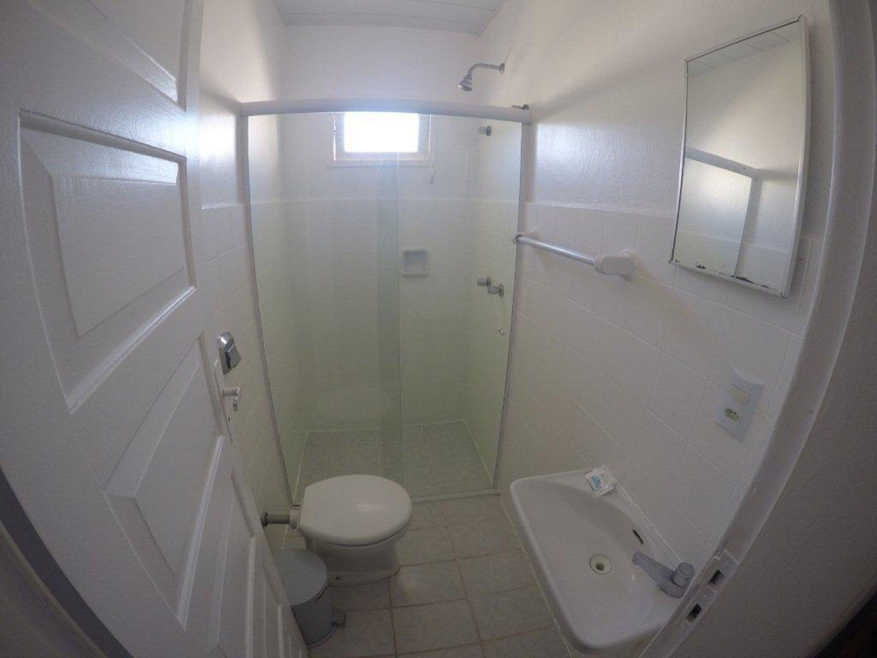 A small, compact bathroom with a toilet, sink, and shower stall.