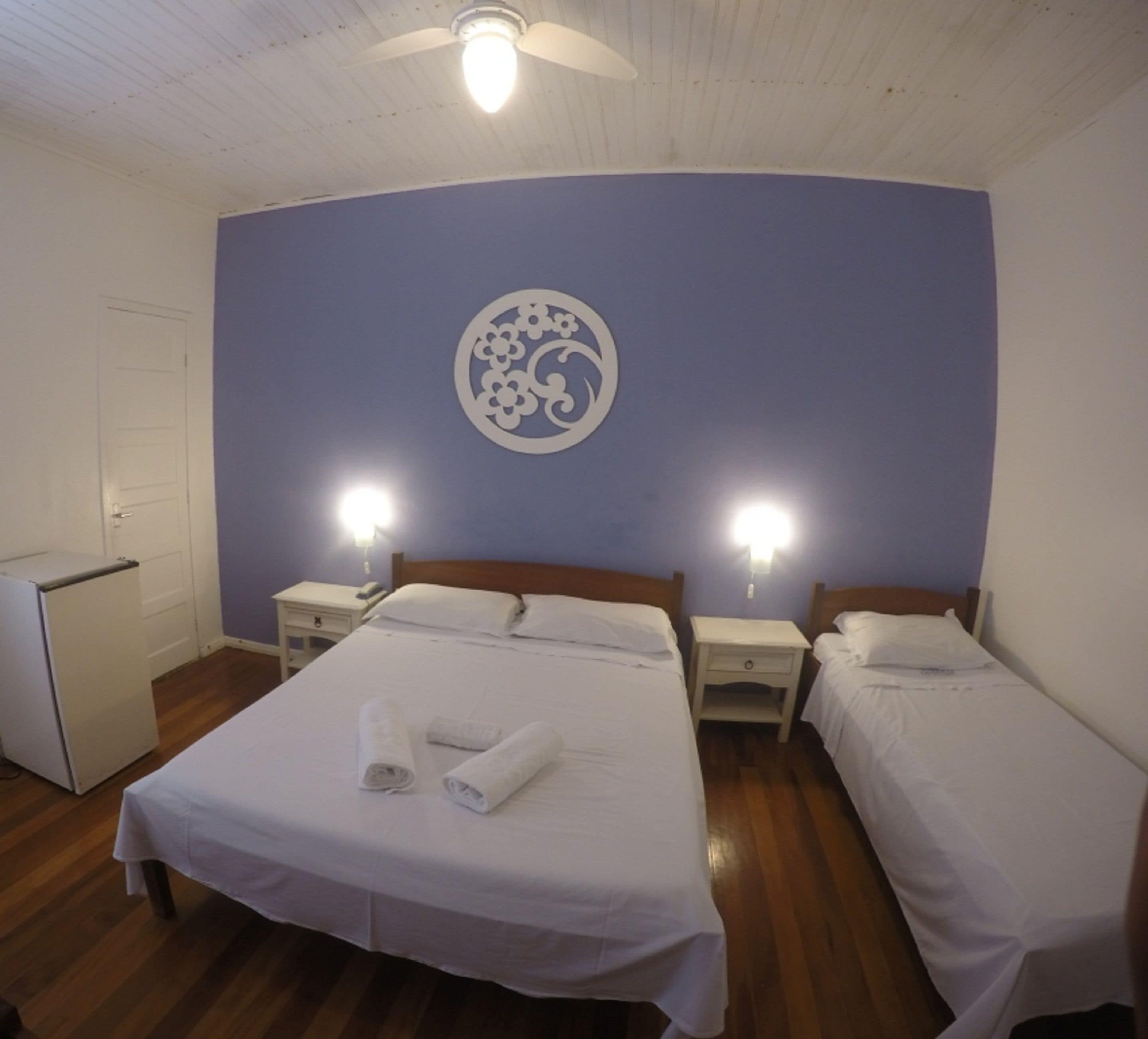 Ein Hotelzimmer mit einem großen Bett, zwei Nachttischen, einem Deckenventilator und einem Wandkunstwerk.