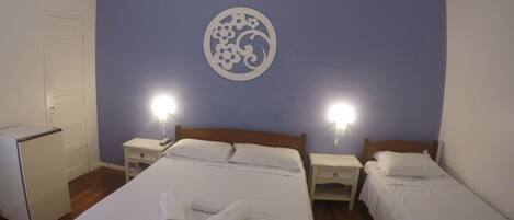 Una habitación de hotel con una cama grande, dos mesitas de noche, un ventilador de techo y un adorno en la pared.