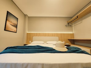 Een hotelkamer met een bed, een nachtkastje, een wandplank en een schilderij.