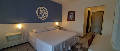 A bedroom with a bed, bedside tables, a wall decoration, and a door.