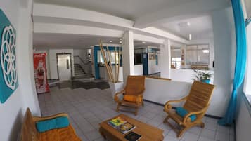 A spacious lobby with a staircase, wooden furniture, and a Coca-Cola refrigerator.
