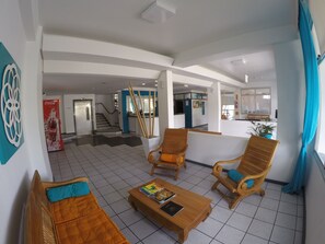 Een ruime lobby met een trap, houten meubels en een Coca-Cola koelkast.