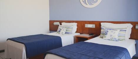 Una habitación de hotel con dos camas individuales, cada una con una colcha azul y almohadas blancas.