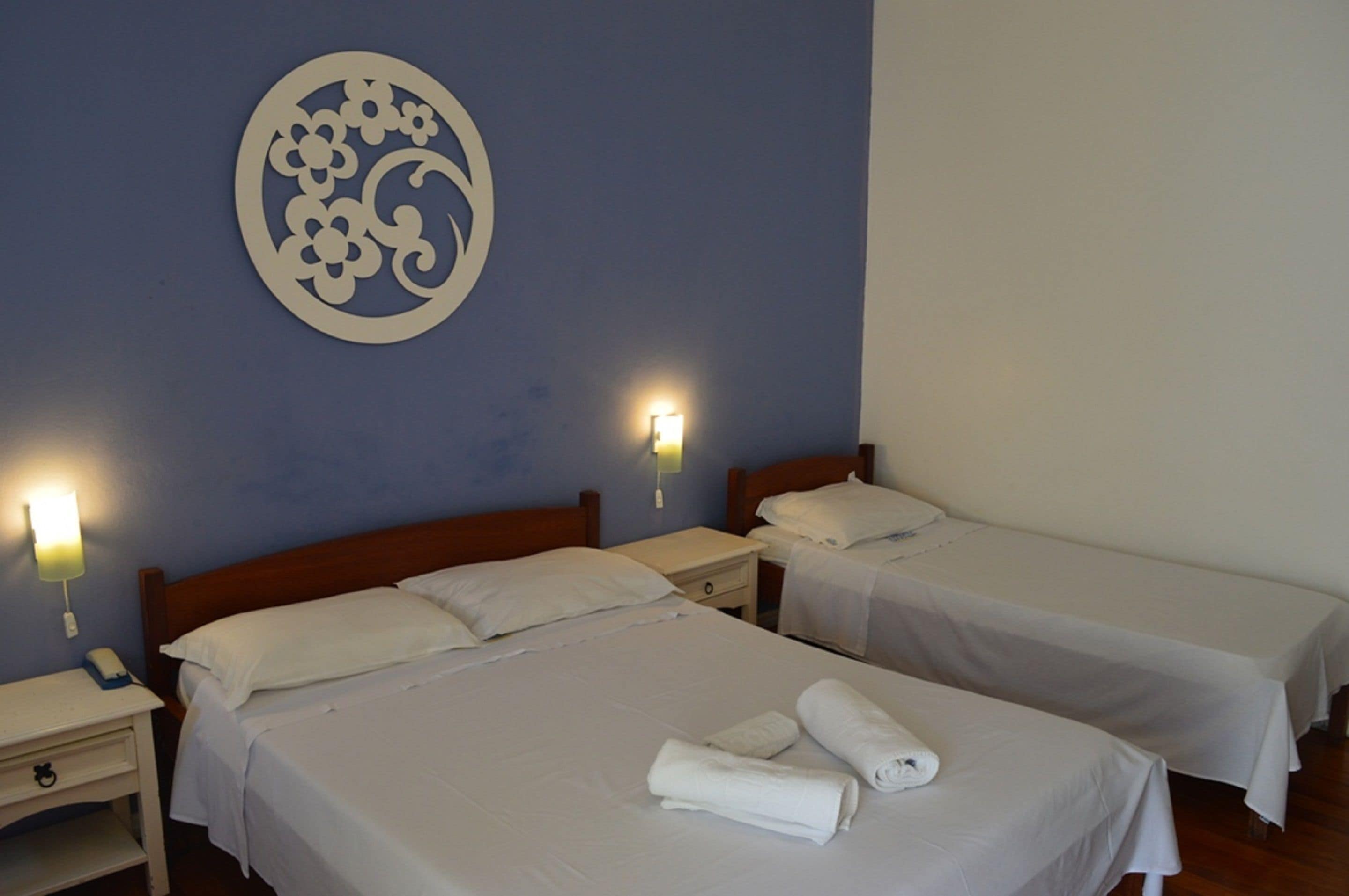 A hotel room with two single beds, a nightstand with a phone, and a wall decoration.