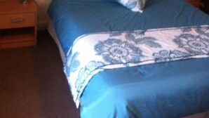 Un dormitorio con una cama, dos mesitas de noche, una mesita auxiliar, un estante en la pared y un cuadro.