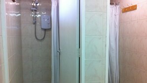 Un área de ducha con cabezal de ducha de mano, puerta de vidrio y un perchero para toallas.
