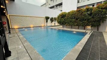 A rectangular swimming pool with a tiled edge, surrounded by a low wall and a hedge.