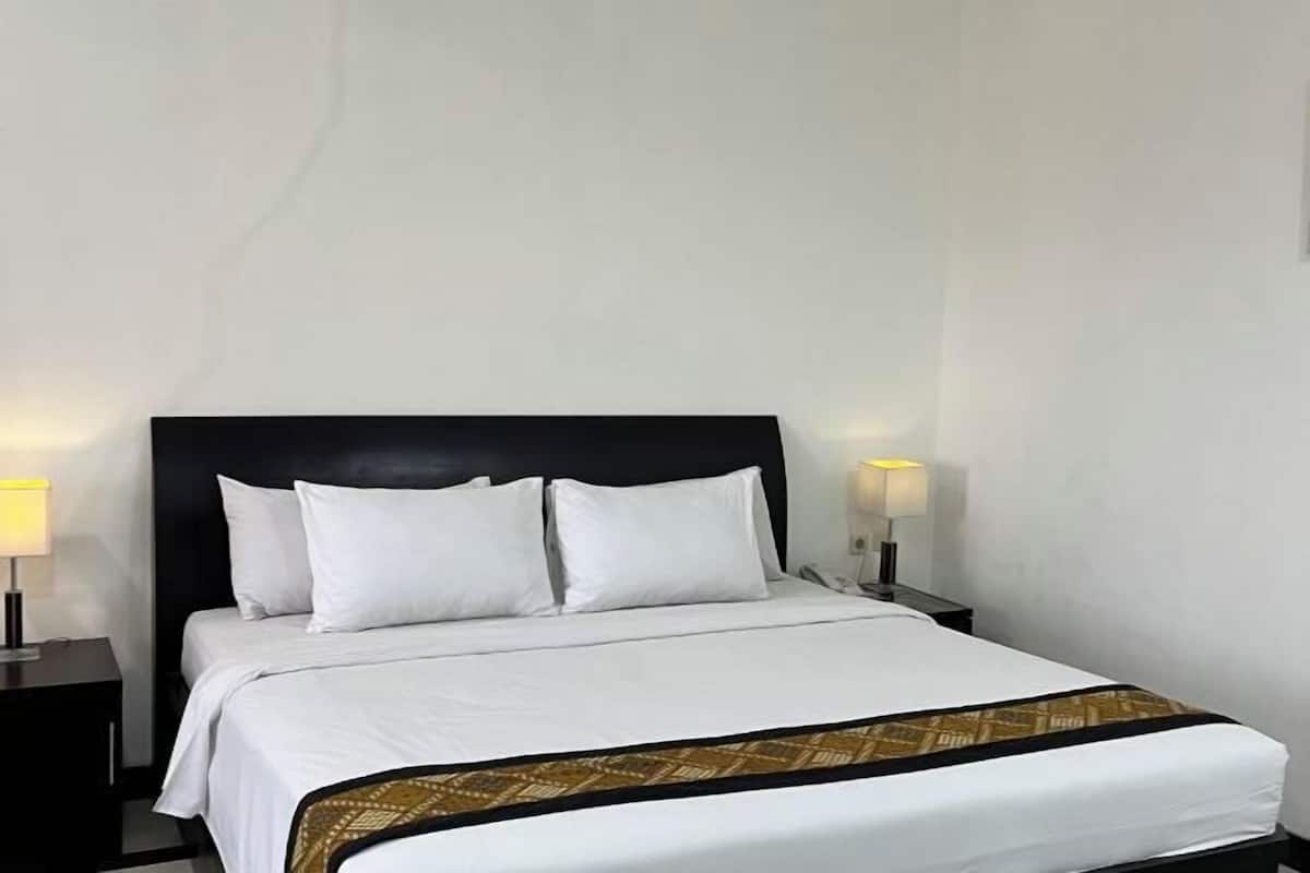 A neatly made bed with white linens, a black headboard, and a patterned throw at the foot of the bed.
