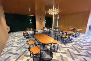 A dining area with multiple tables and chairs, a patterned floor, and a modern chandelier. - Riez Palace Hotel (East Tegal)