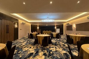 Un salón de conferencias con mesas redondas, sillas y suelo alfombrado.