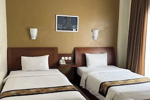 A hotel room with two beds, a nightstand with a phone, and a framed picture on the wall.