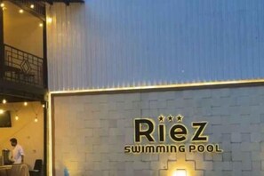 A swimming pool named 'Riez' with a sign on a brick wall. - Riez Palace Hotel (East Tegal)