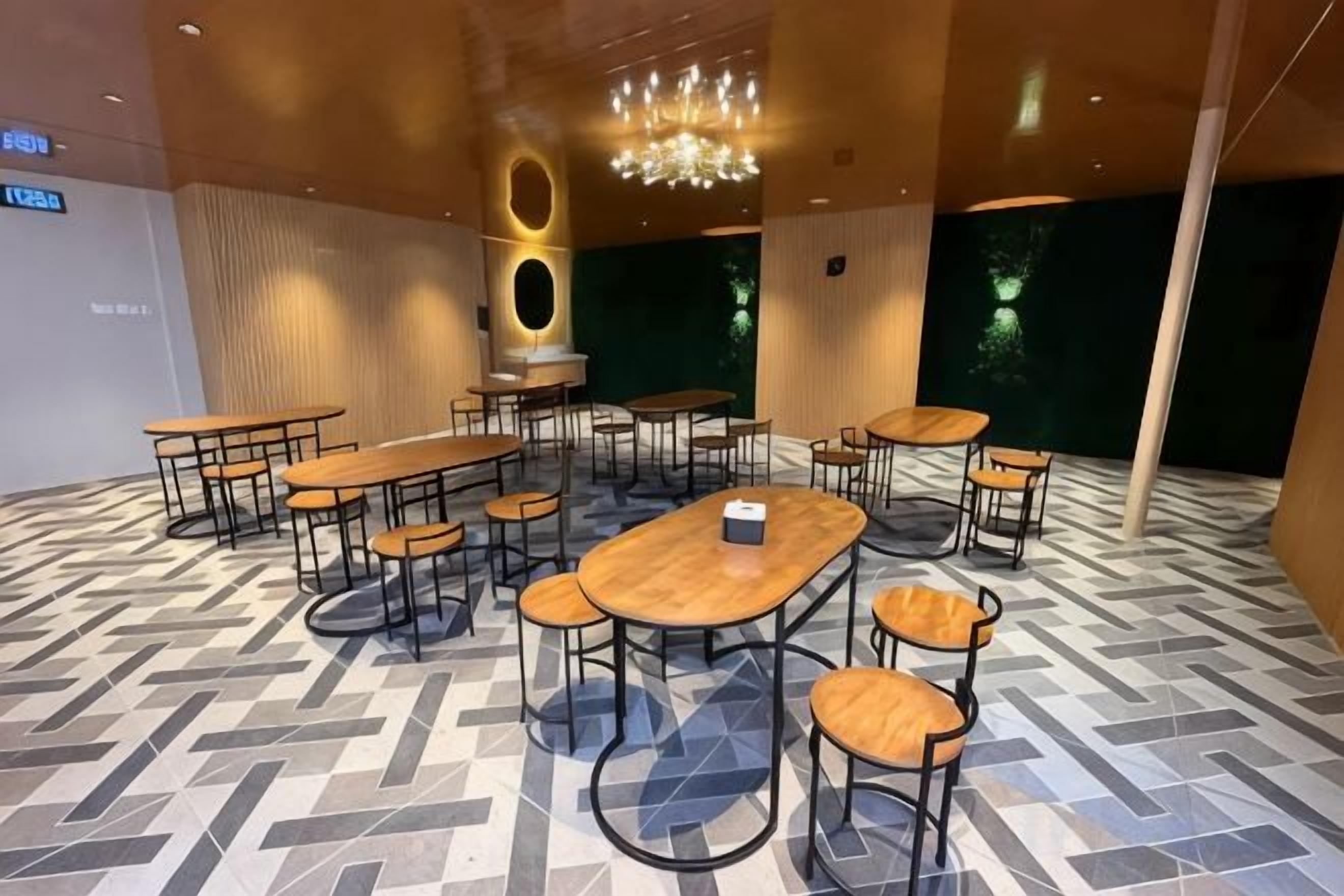 Un salón de conferencias con varias mesas y sillas, una araña y un suelo estampado.