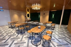Un salón de conferencias con varias mesas y sillas, una araña y un suelo estampado.