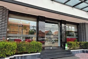 A hotel entrance with a glass facade, steps leading up to the door, and a clear view of the street outside. - Riez Palace Hotel (East Tegal)