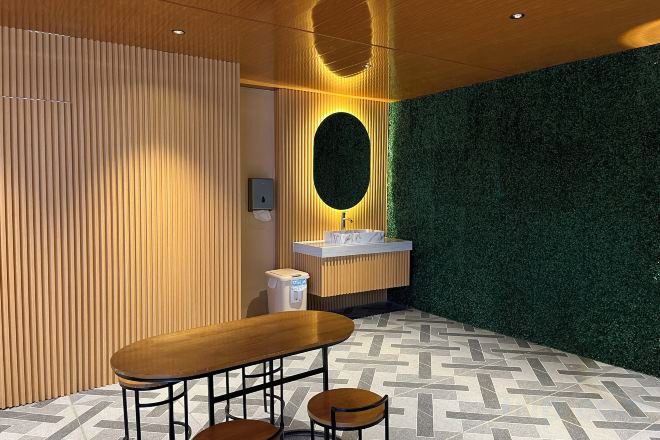 A bathroom with a wooden vanity, a mirror, and a patterned floor.