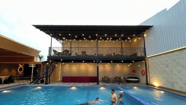 An indoor swimming pool with a covered seating area and a stage. - Riez Palace Hotel (East Tegal)