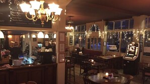 A restaurant with multiple seating areas, a bar, and a view of the street outside. - The Kings Arms (London)
